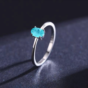 Silver ring with a blue gemstone on a dark background