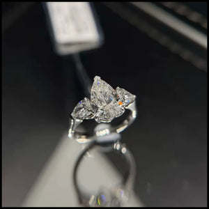 Diamond Moissanite ring with three pear-shaped diamonds on a reflective surface