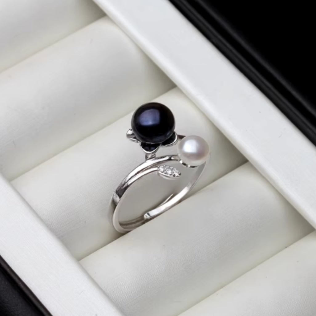 A Pearl Silver Adjustable Ring with a solid silver band and two pearls, one white and one black, set in the band.