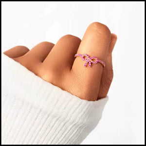 Pink Zircon Bow Ring on finger with white sleeve background, minimalist and elegant jewelry design