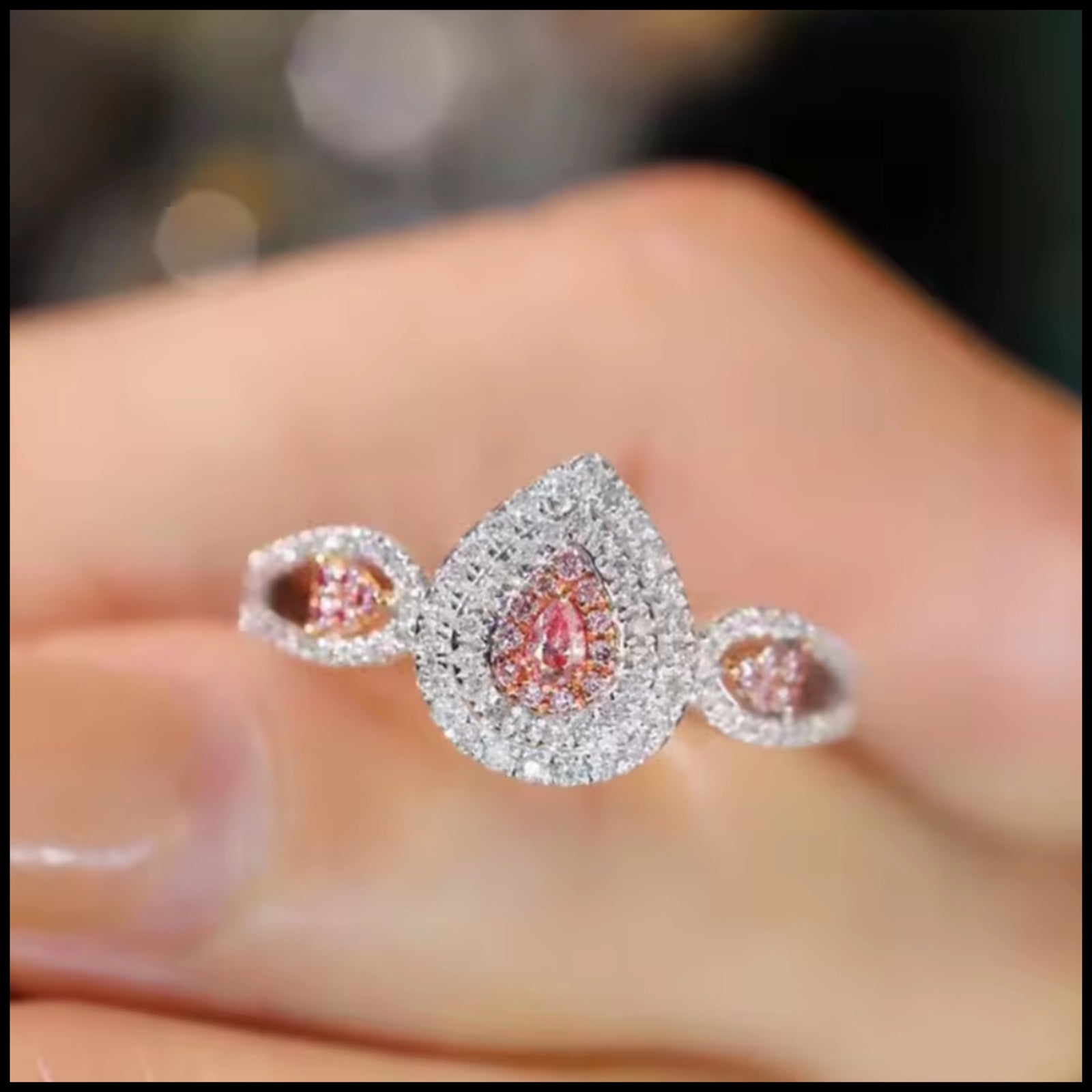 Delicate ring with pink gemstones on a blurred hand background