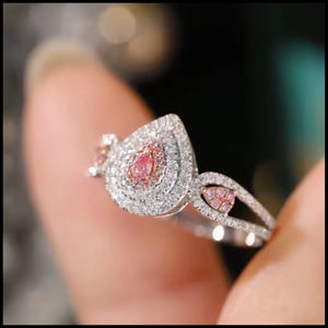 Close-up of a diamond ring with pink gemstones on a blurred background