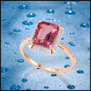 Rose gold ring with a pink gemstone on a blue water droplet background