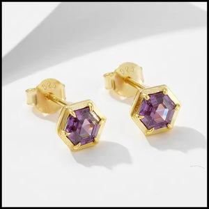 Gold earrings with purple gemstones on a white background