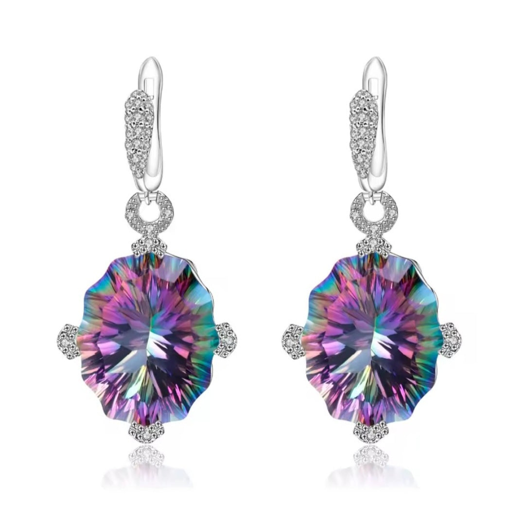 A pair of silver drop earrings featuring large, natural mystic quartz round iridescent gemstones that shift between purple, blue, green, and pink, accented by small clear stones in a halo setting and lever back hooks.