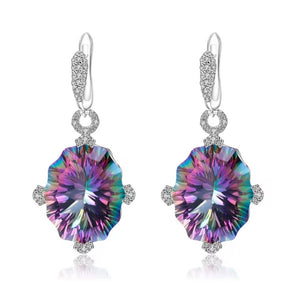 A pair of silver drop earrings featuring large, natural mystic quartz round iridescent gemstones that shift between purple, blue, green, and pink, accented by small clear stones in a halo setting and lever back hooks.