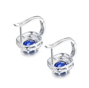Sapphire Diamond 18K Gold earrings with vivid blue round sapphires in polished silver-tone settings and hinged backs.