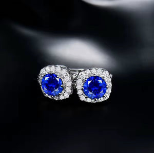 Sapphire Diamond 18K Gold stud earrings with vivid blue round sapphires, surrounded by sparkling diamonds in white gold.