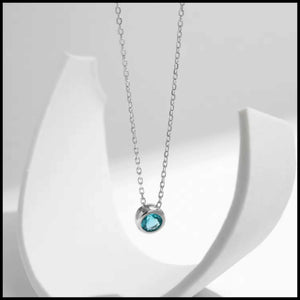 Silver necklace with a blue gemstone pendant on a white background