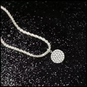 Necklace with a round, diamond-studded pendant on a black textured background