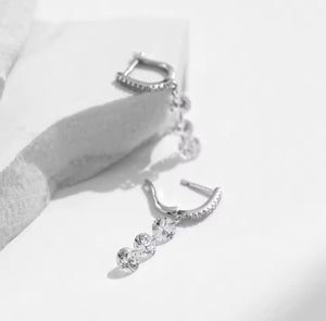Silver earring with three clear gemstones on a white background