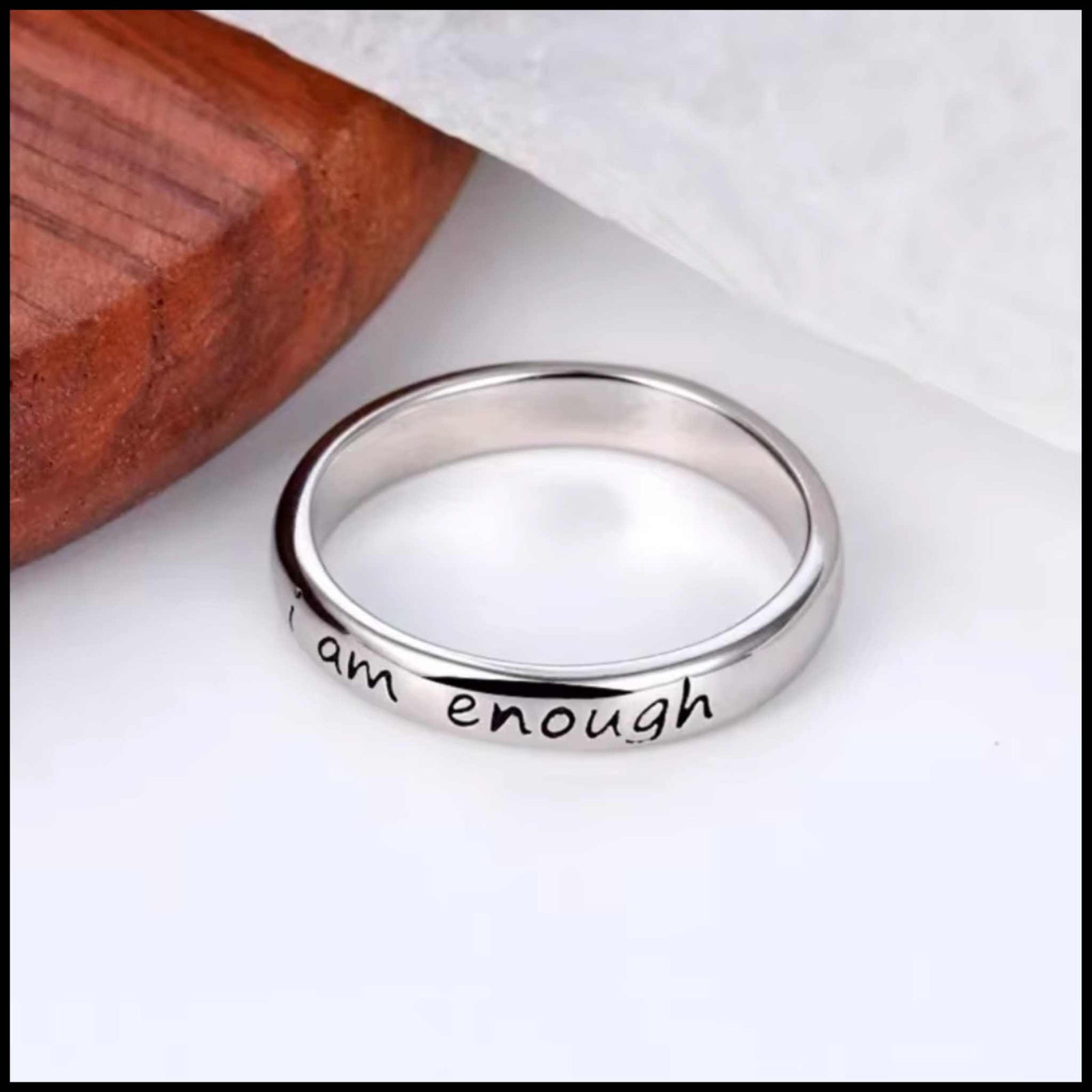 Silver ring with 'I am enough' engraving on a white background.