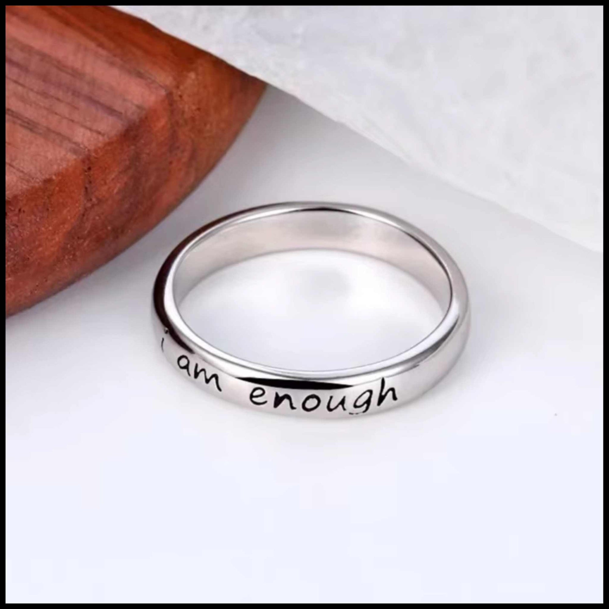 Silver ring with 'I am enough' engraving on a white background.
