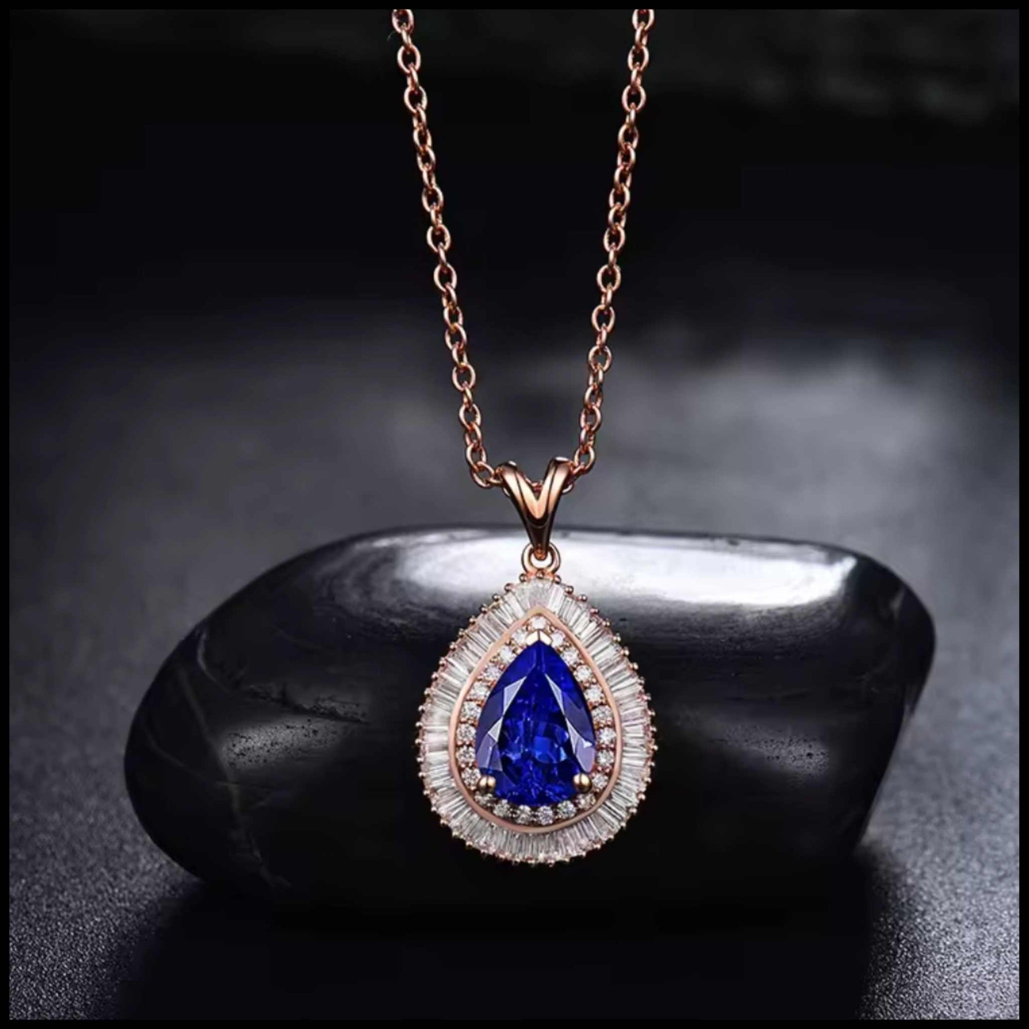 Elegant pear-shaped tanzanite diamond rose gold necklace on black stone background