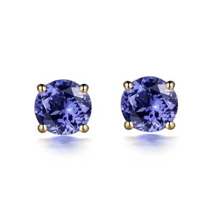 A pair of round-cut tanzanite stud earrings set in yellow gold prong settings, shown on a clean white background with soft reflections below.