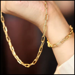 Gold chain necklace and bracelet on a wrist against a blurred background