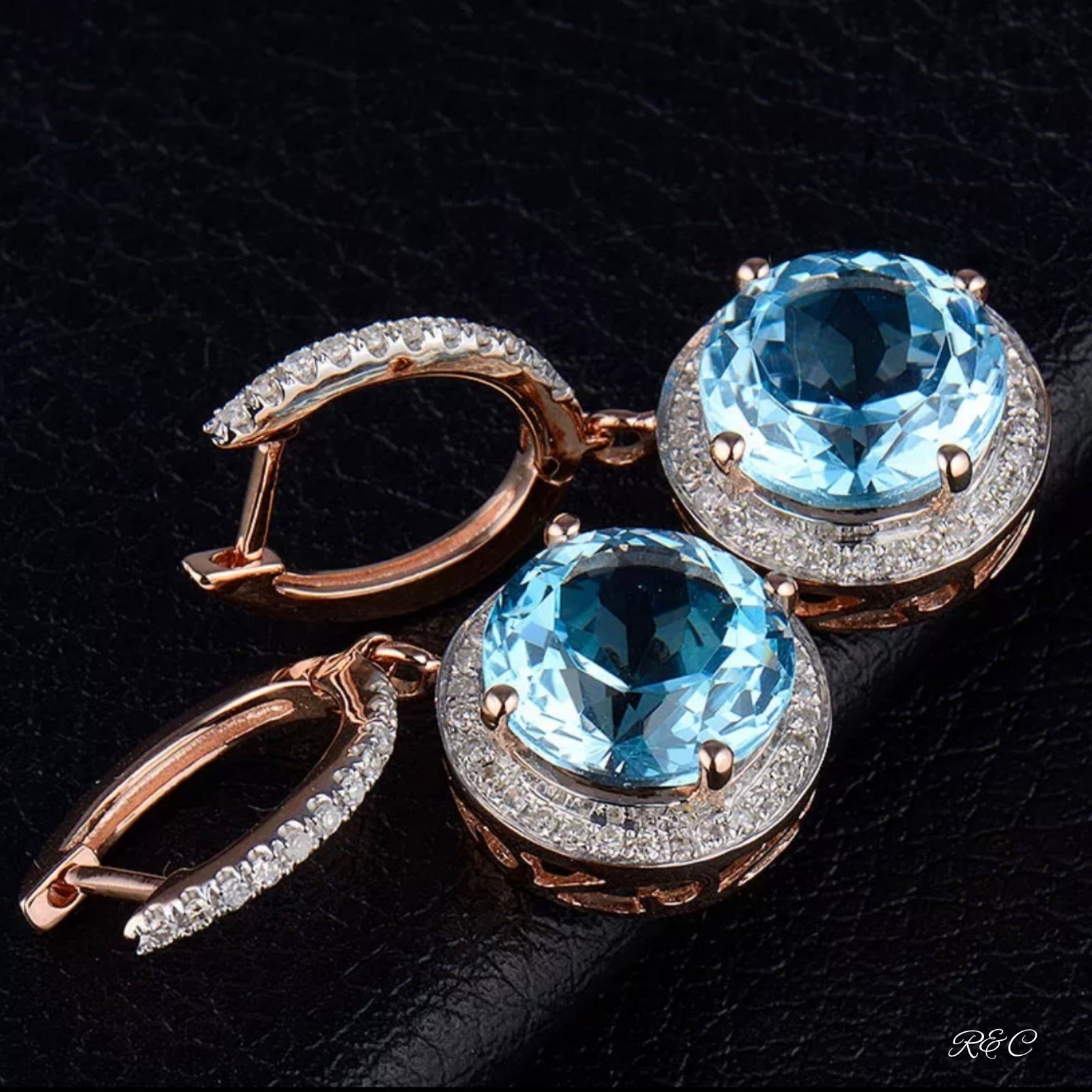 A pair of vintage style earrings with blue topaz and diamonds, held against a black background.