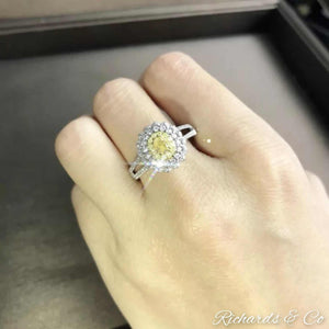 Yellow and white halo engagement diamond ring with oval yellow center stone in 18K white gold