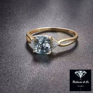14k yellow gold ring with cushion cut blue topaz and diamond accents, prong setting, elegant design