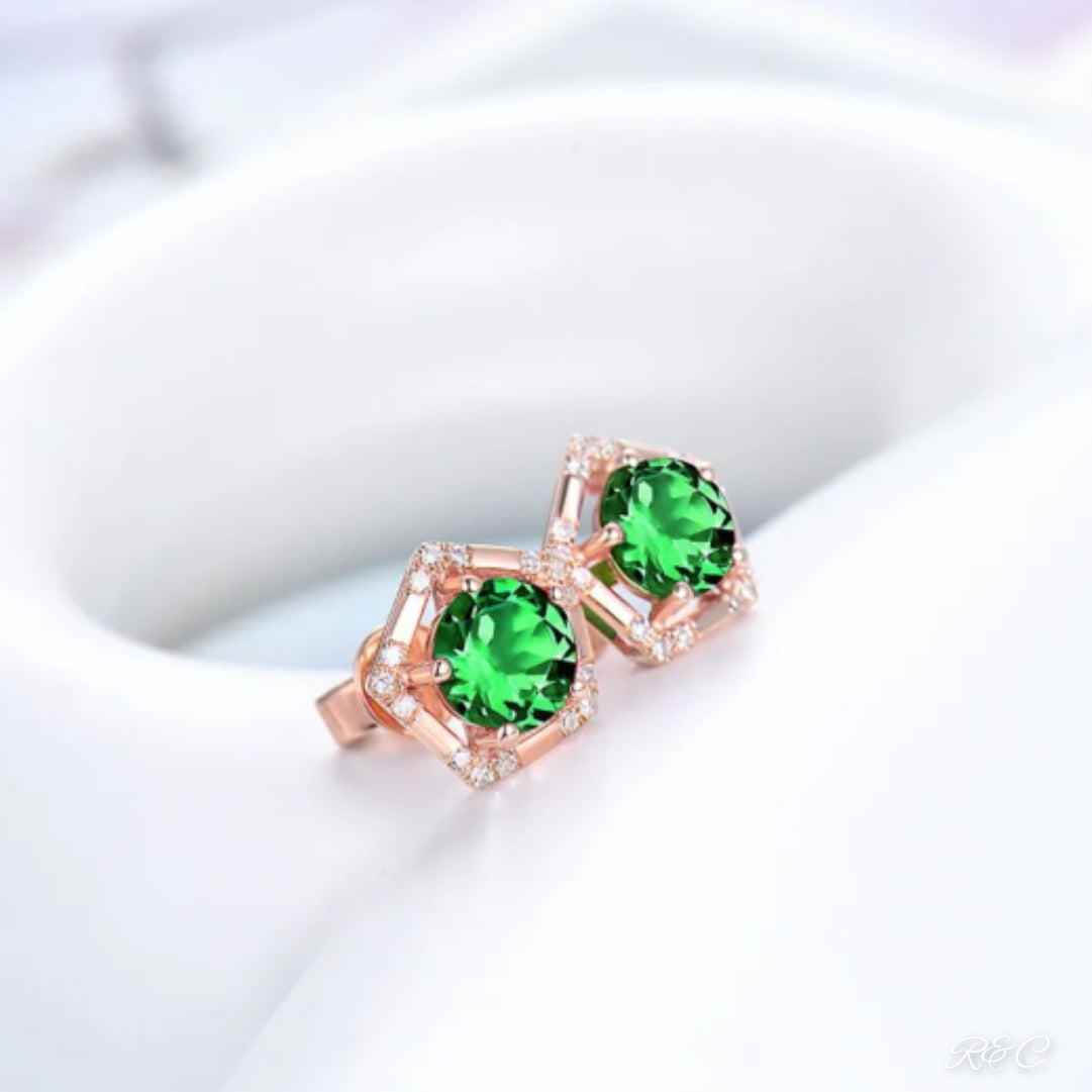 A pair of rose gold stud earrings, featuring a round-cut green tsavorite and a round-cut natural diamond.
