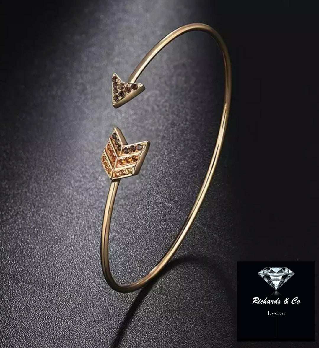 Delicate gold bangle bracelet with smokey quartz and citrine arrowhead accents on dark background