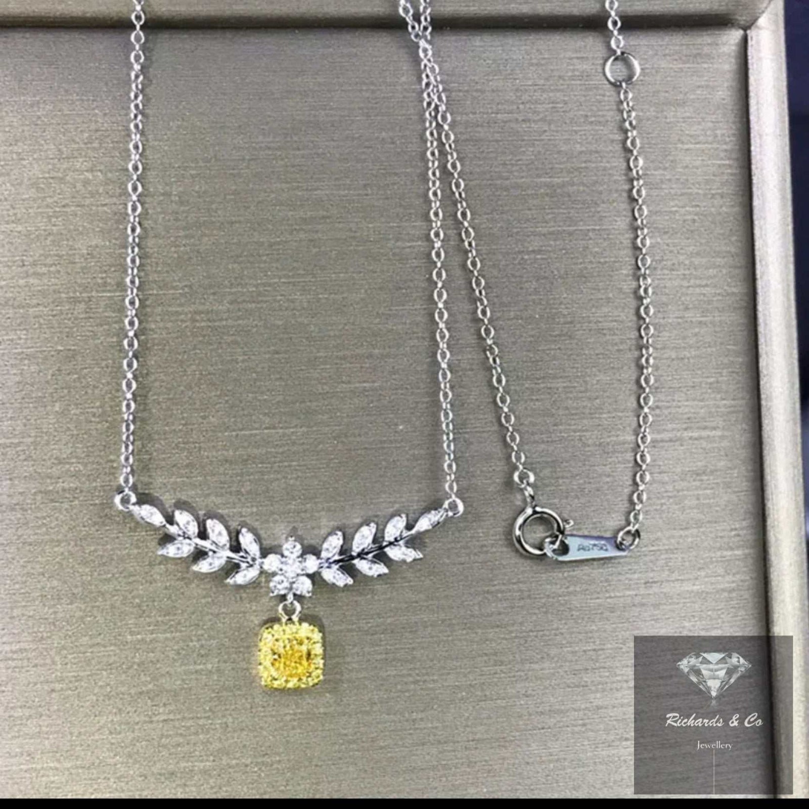 Elegant yellow diamond necklace with white gold chain and leaf-shaped white diamonds