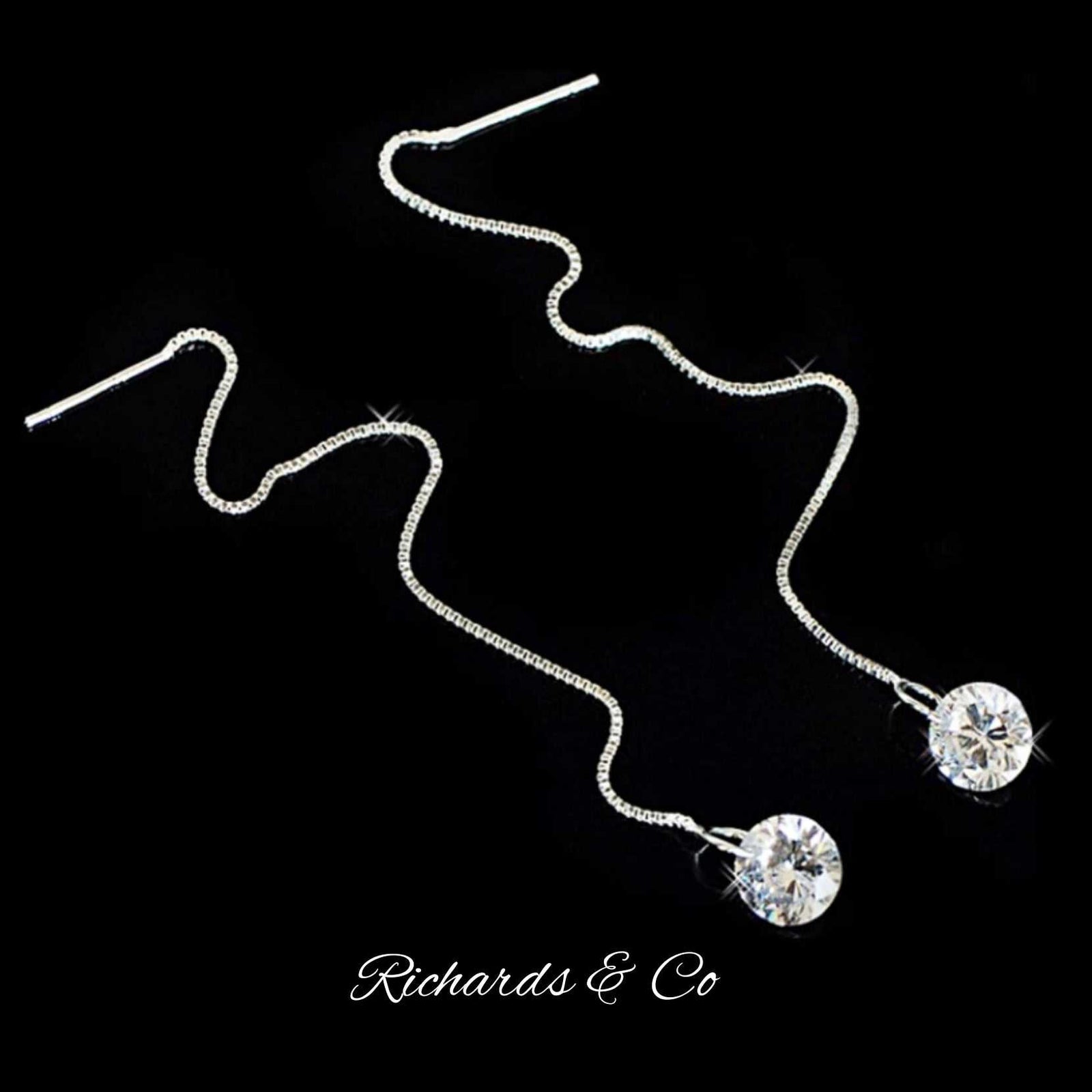 Handcrafted silver long drop earrings with cubic zirconia crystals and adjustable length chains on black background