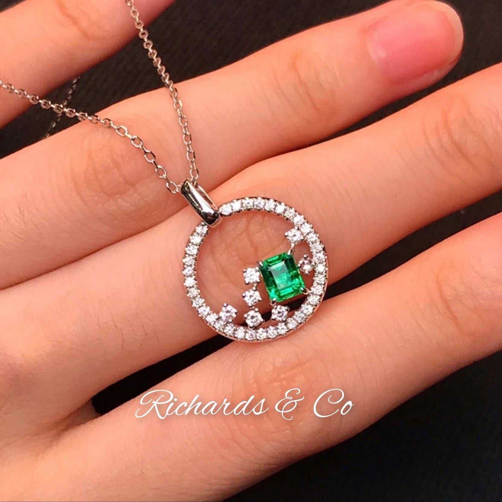 18k white gold emerald and diamond necklace with round pendant and link chain on hand