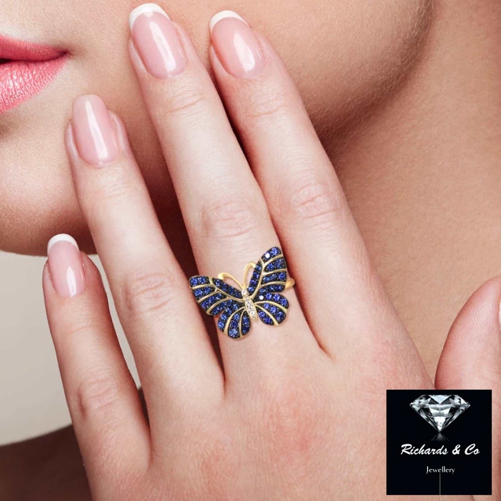 Yellow gold butterfly ring with blue sapphires and white topaz on a woman's finger