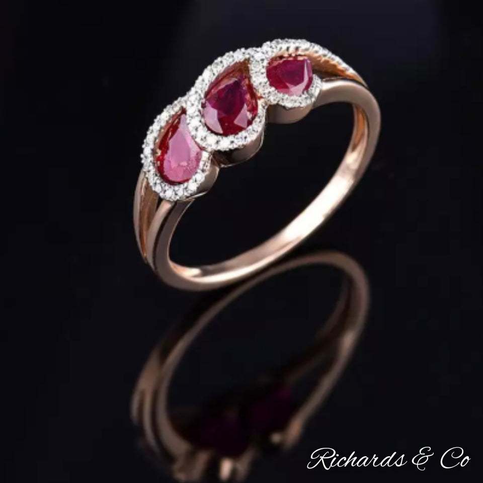 Ruby and diamond rose gold ring with pear-shaped rubies and round cut diamonds on black background