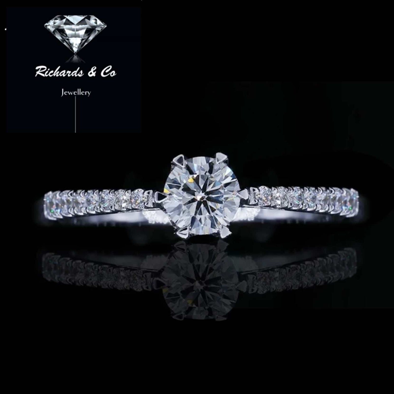 Diamond band white gold ring with natural round center diamond and side diamonds in prong setting.