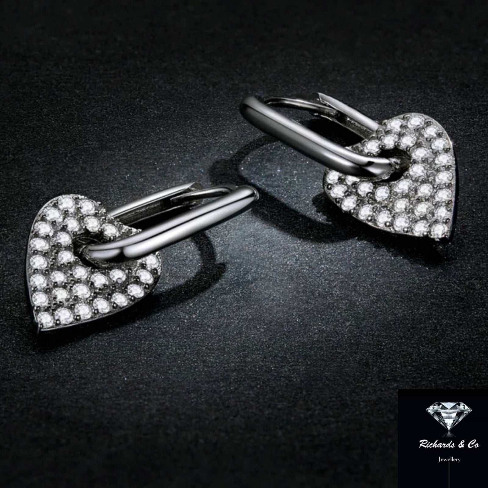 Silver heart buckle earrings platinum plated with cubic zirconia stones on black background