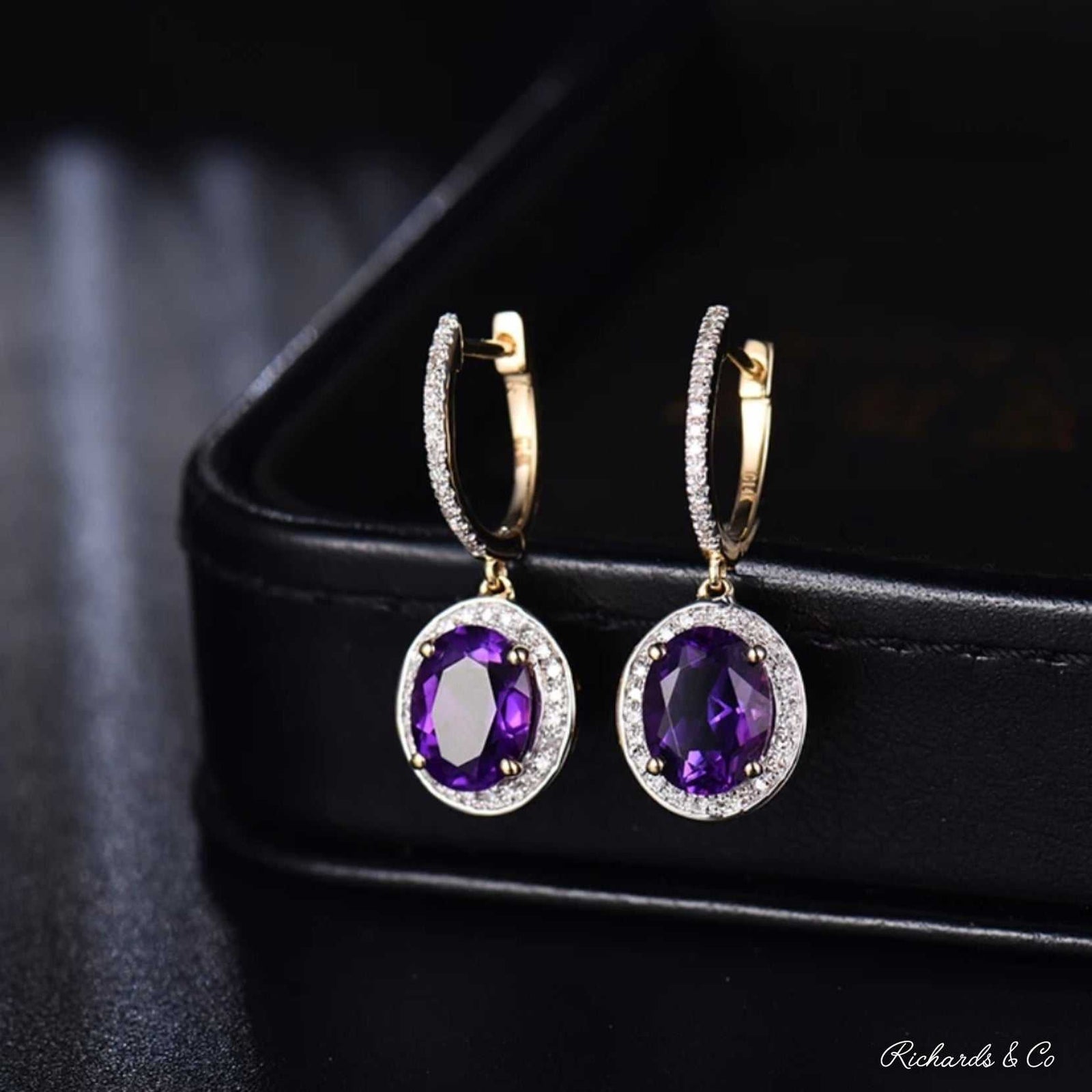 Elegant purple amethyst and diamond drop earrings set in 14k yellow gold with oval amethyst stones and sparkling diamonds